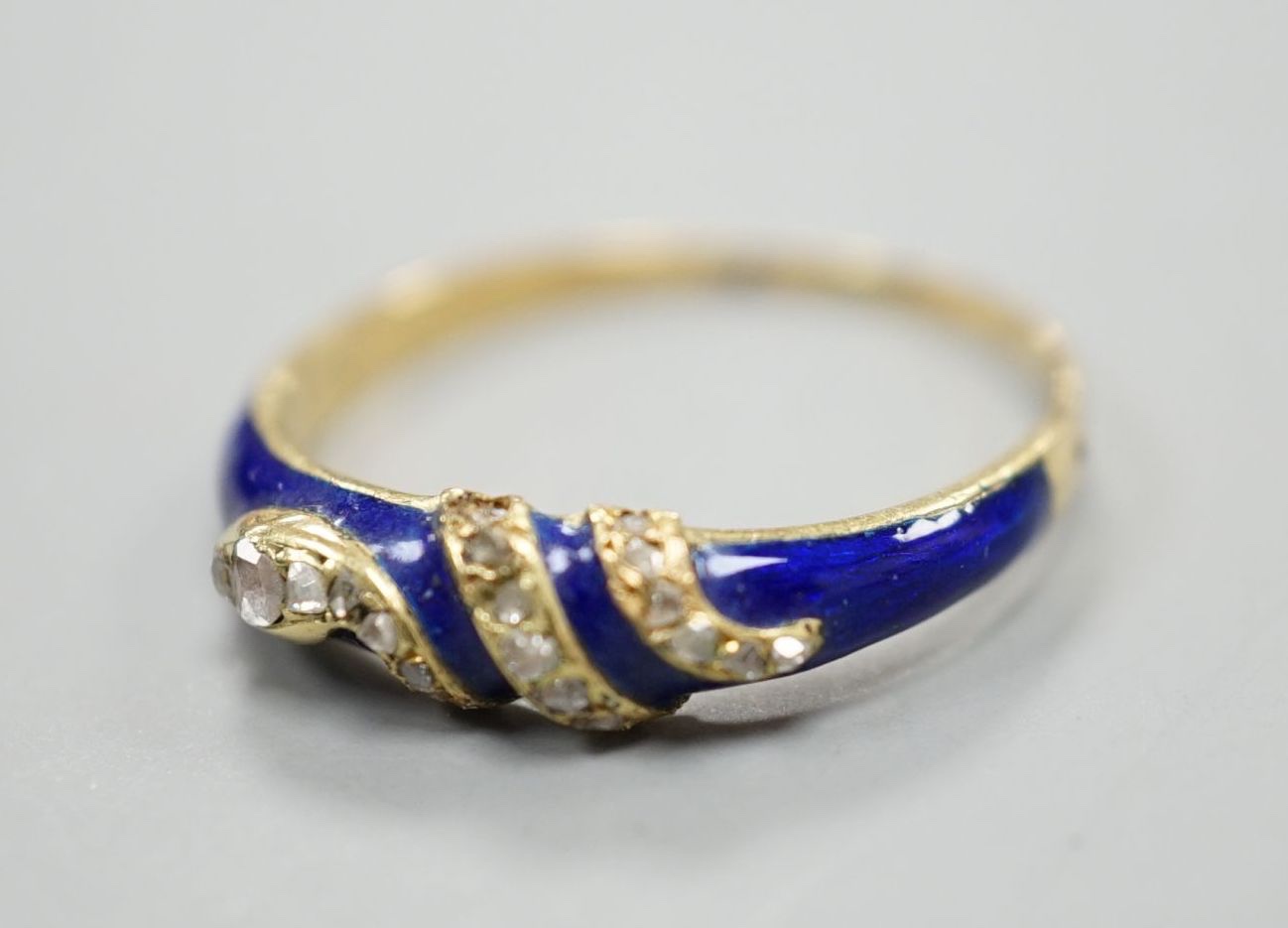 A late Victorian yellow metal, blue enamel and rose cut diamond set serpent ring, size O, gross weight 2.5 grams.